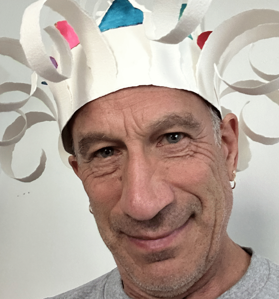 Roger Goldenberg in a white paper crown with curls