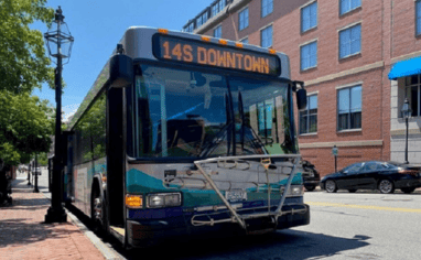 A Coast Bus stopped by a sidewalk