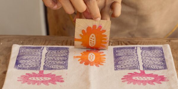 Hands pull off a flower stamp from a printmaking project